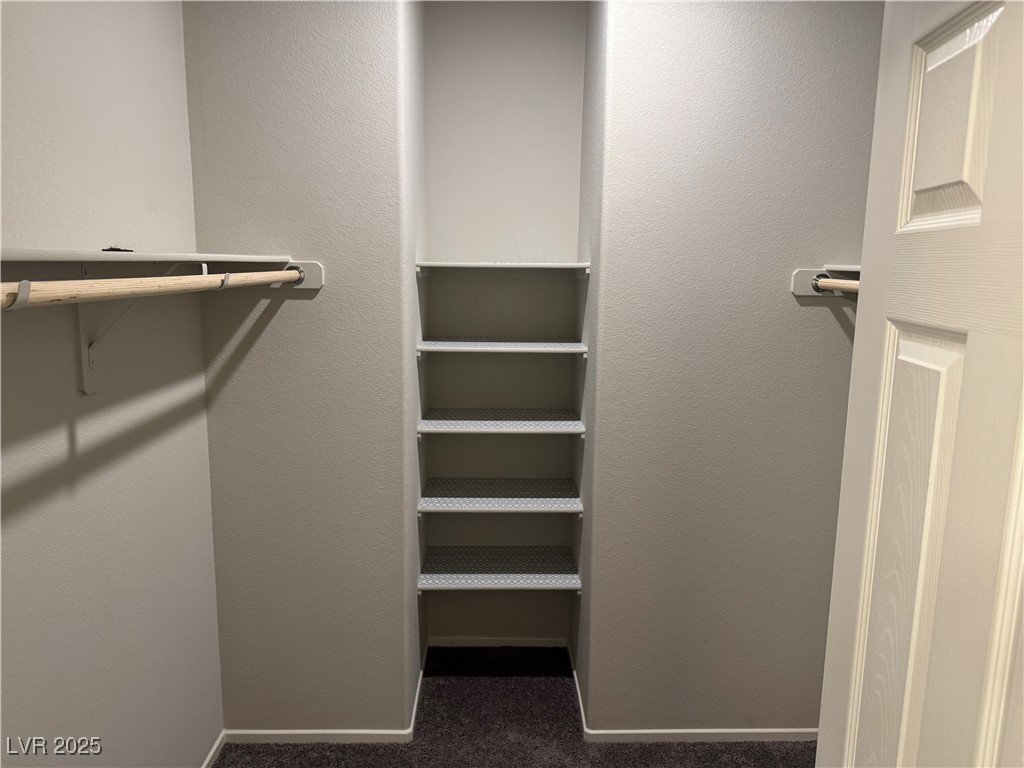 Empty closet with built-in shelves and hanging rods along both side walls.