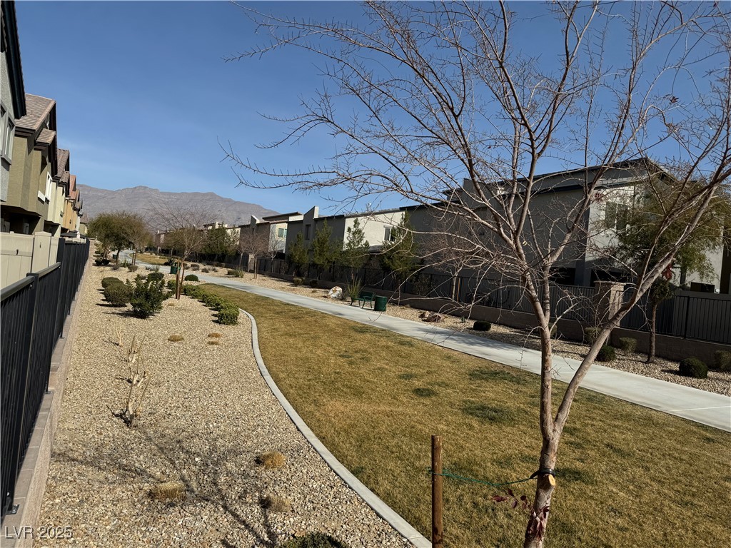Residential community walkway with gravel landscaping, a central lawn, and mountains in the distance.
