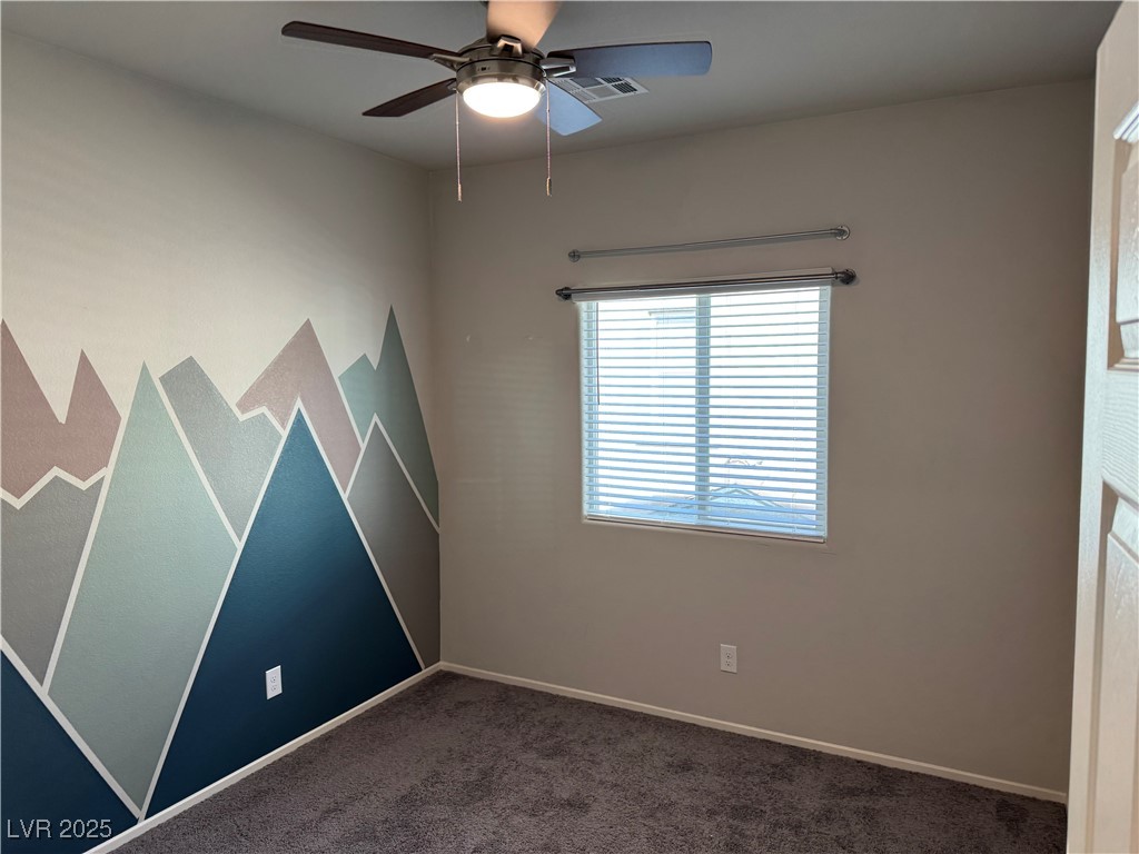 Empty bedroom with a geometric mountain mural, carpet, ceiling fan, and window blinds.