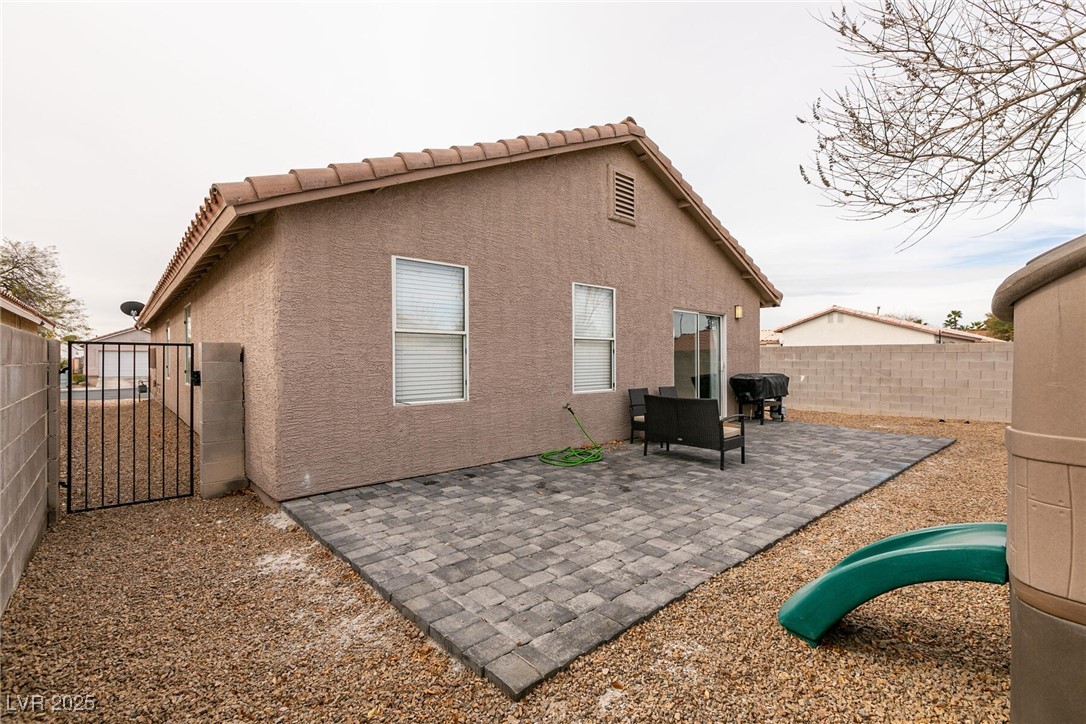 Backyard patio with gray pavers, gravel landscaping, outdoor seating, and a gated side yard.