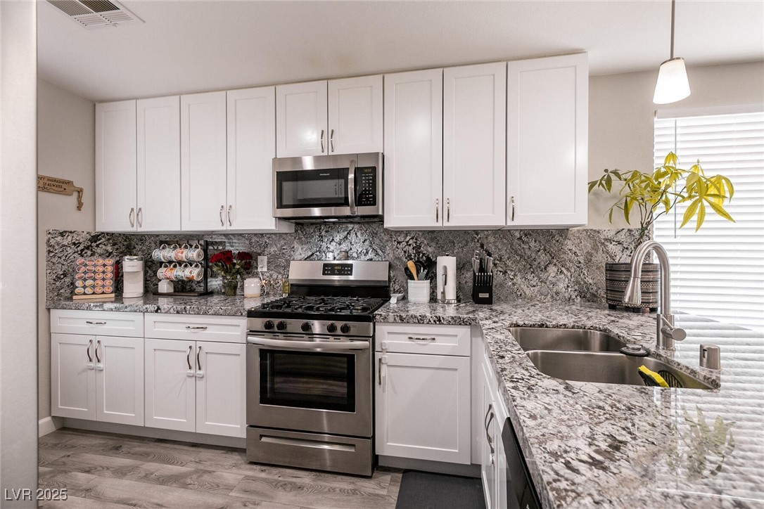 Kitchen with white cabinets, granite counters, stainless steel appliances, and a double-basin sink.