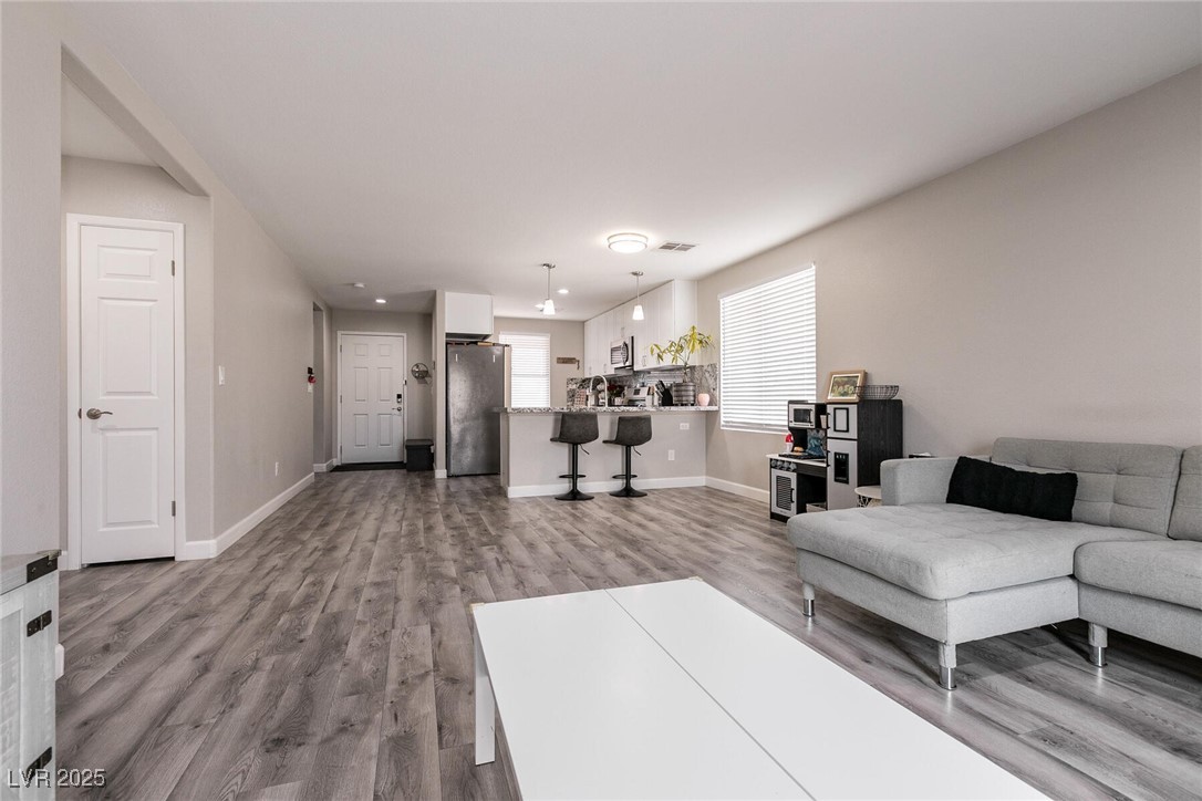 Open-plan living room with a gray sectional, white coffee table, and kitchen breakfast bar.