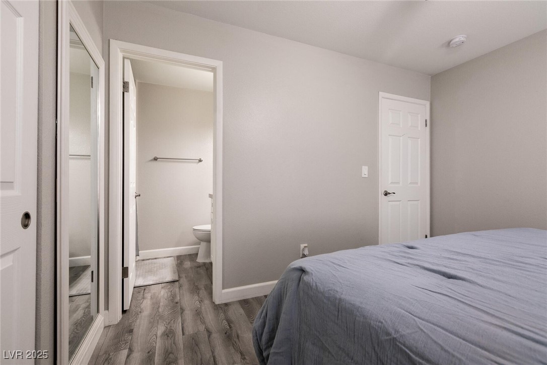 Bedroom with blue-gray bedding, mirrored closet doors, and an open doorway to the bathroom.
