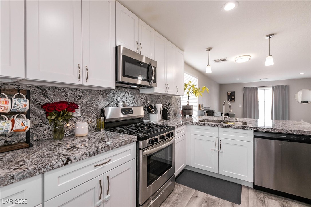Kitchen with white cabinets, granite counters and backsplash, and stainless steel appliances.