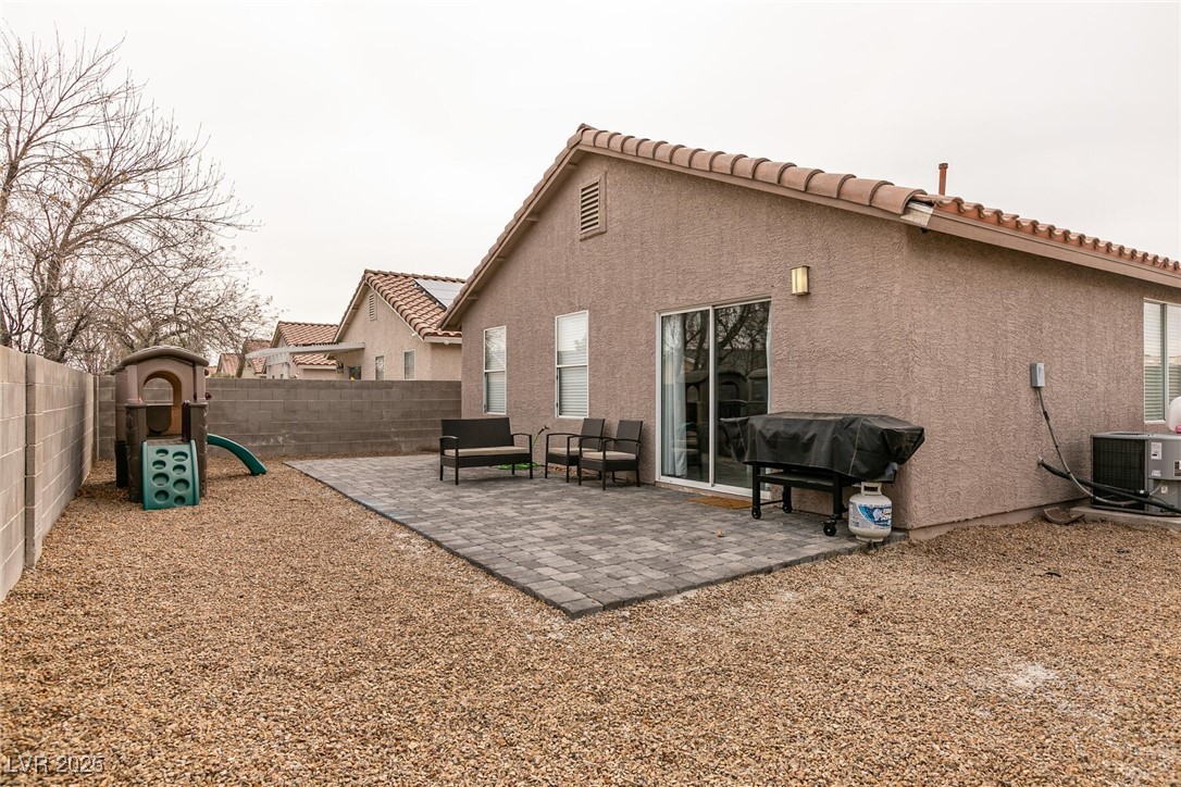 Home backyard with a paver patio, gravel landscaping, outdoor seating, and a small play structure.