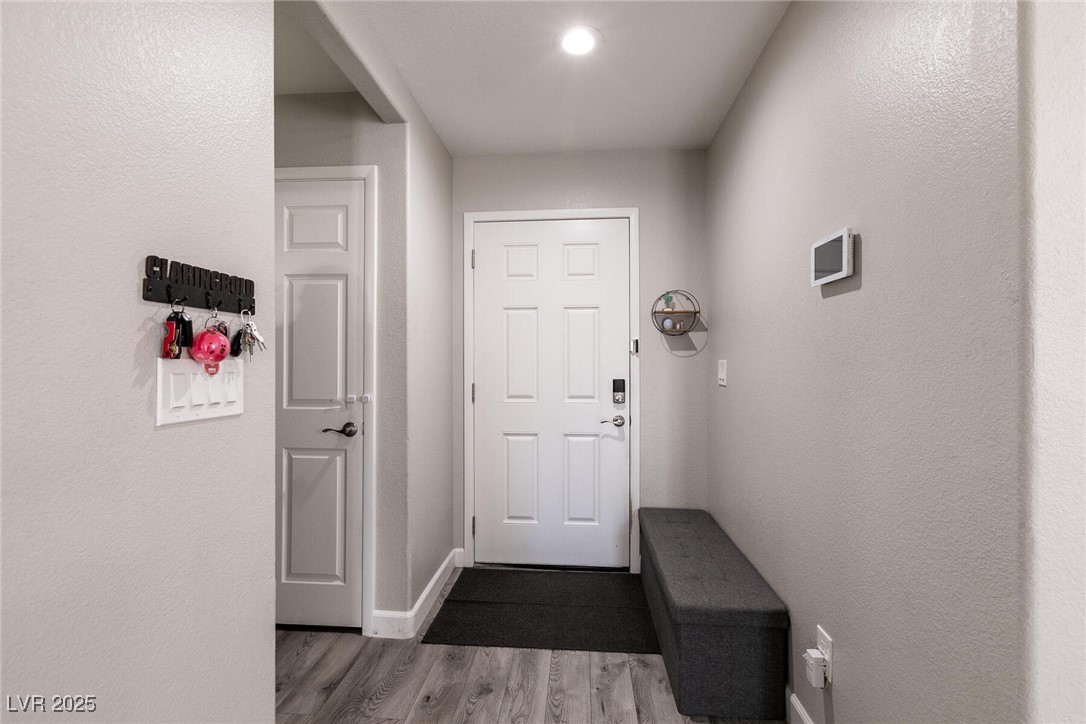 Entry foyer with a white paneled front door, gray bench, and wood-look flooring.