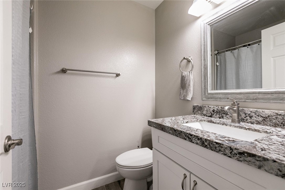 Bathroom with a granite vanity, large mirror, and toilet.