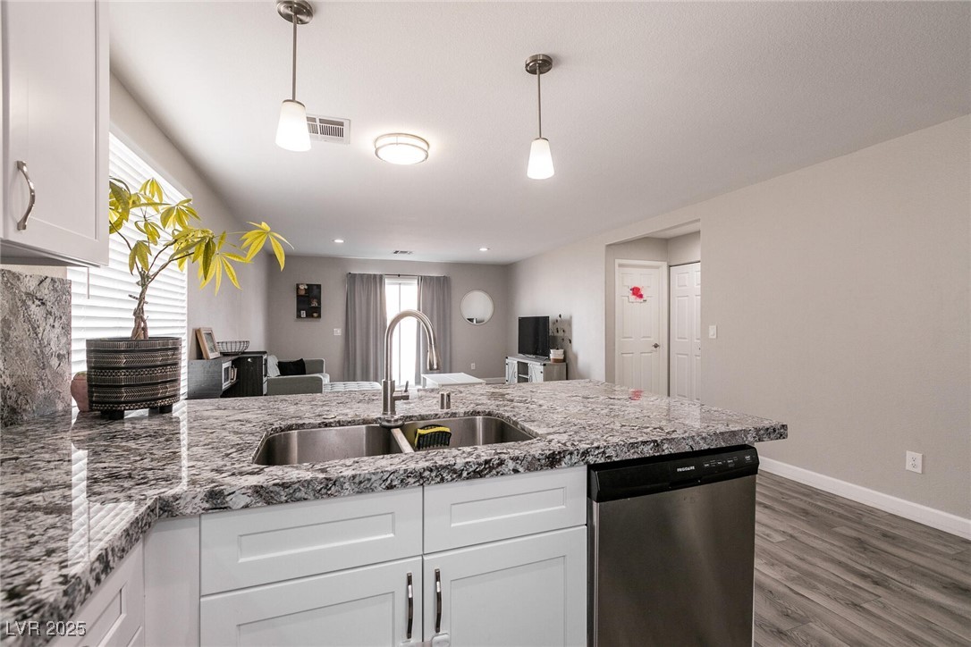 Open-plan kitchen with a granite island and double sink, looking toward the living area.