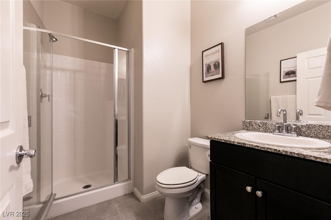 Bathroom with a glass shower and dark granite-topped vanity.