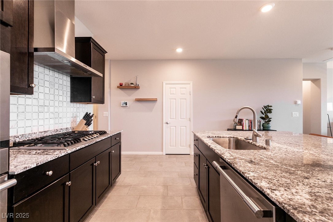 Kitchen with dark wood cabinets, granite counters, gas cooktop, and a large island with a double-basin sink.