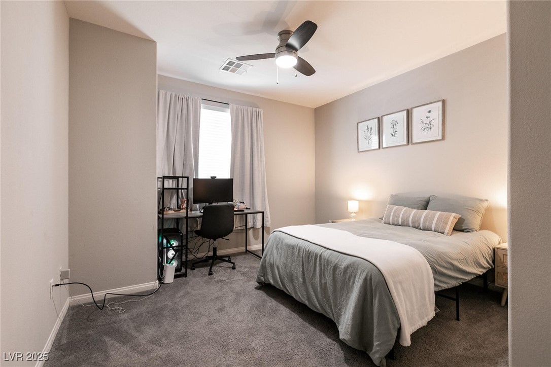 Bedroom with a gray bed, desk and computer, curtained window, and ceiling fan.