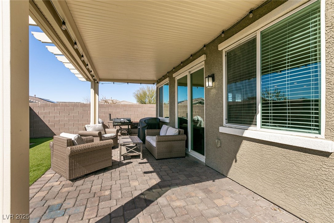 Covered patio with wicker seating, paver flooring, and a strip of artificial turf.
