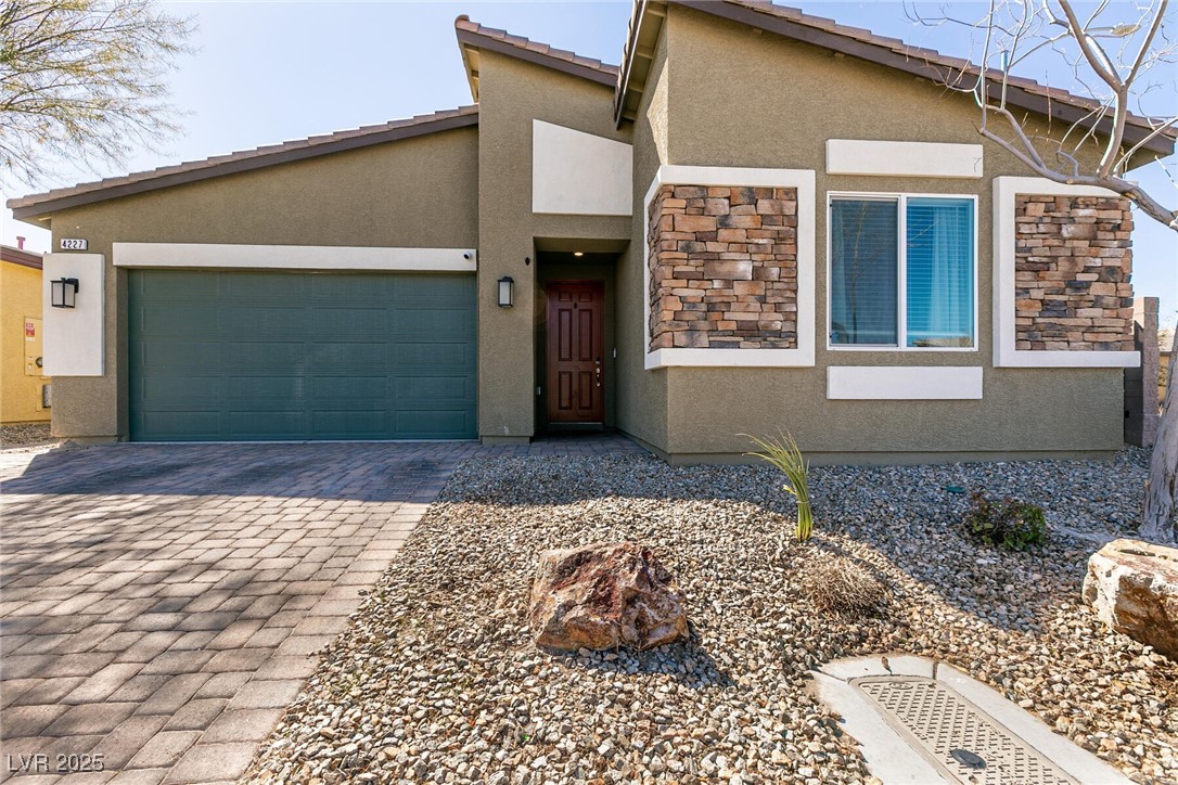 Home exterior with a two-car garage, stone window accents, and rock landscaping.