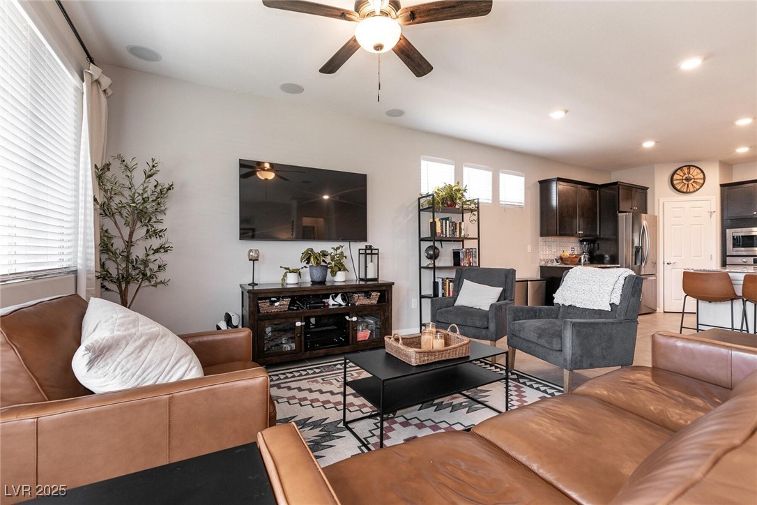 Living room with brown leather sofas, gray armchairs, and an open kitchen.