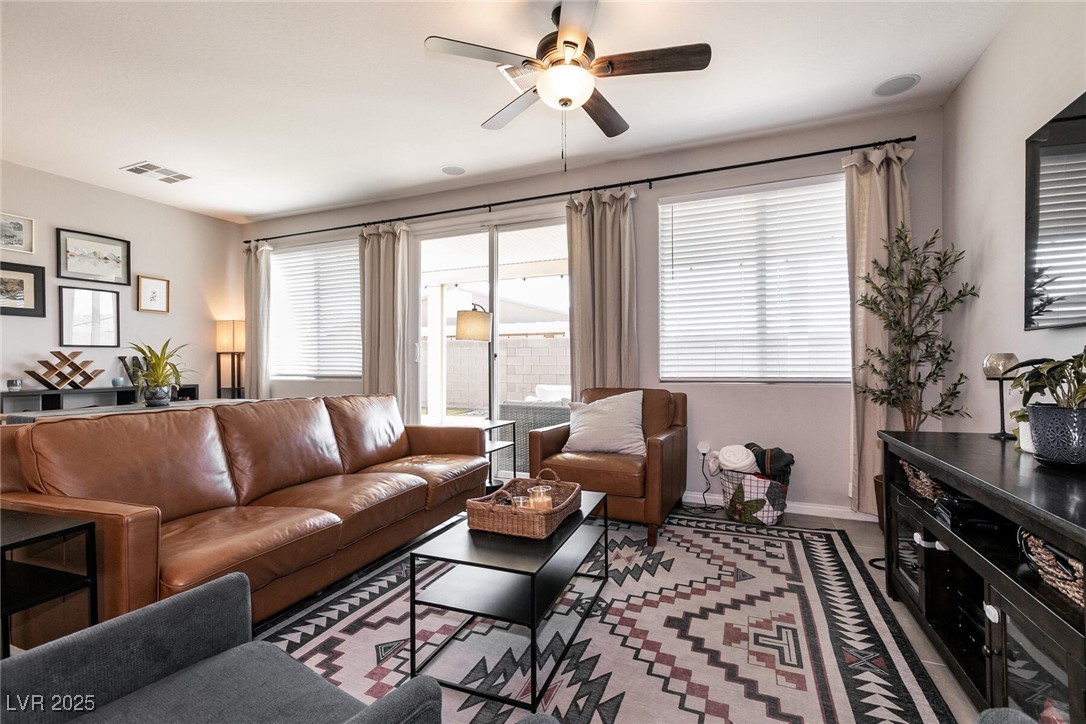 Furnished living room with a brown leather sofa, patterned rug, and sliding glass doors to a walled patio.