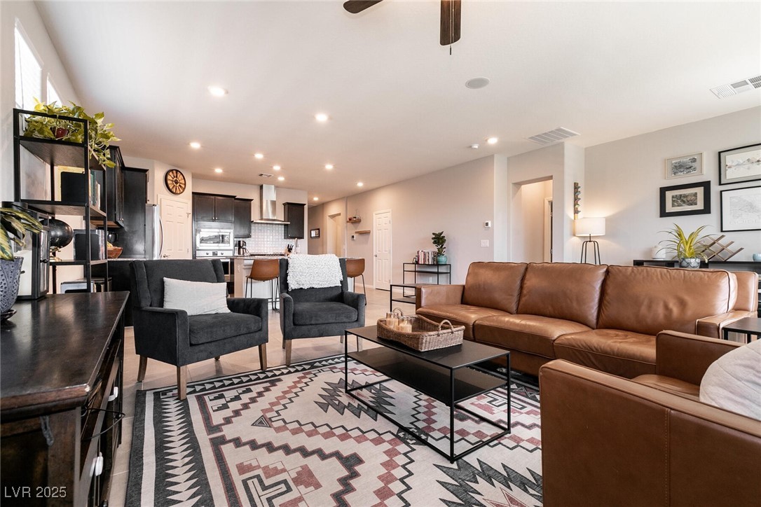 Open-plan living room with a brown leather sofa, charcoal armchairs, and a geometric rug.