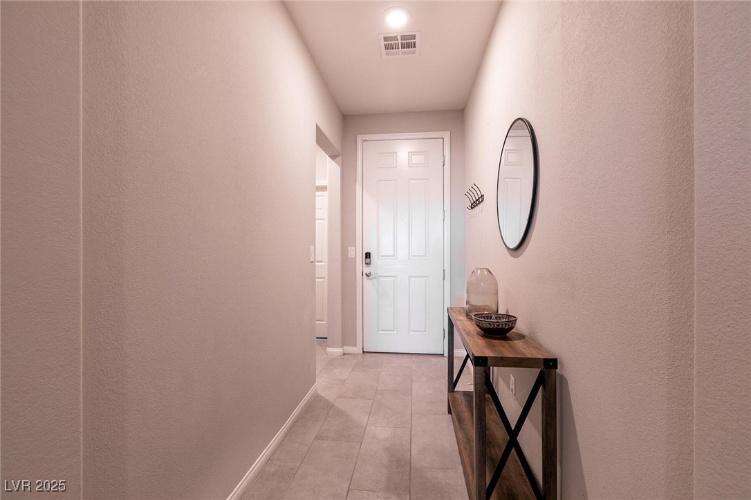 Entry hallway with tiled floor, white front door, and wooden console table beneath an oval mirror.