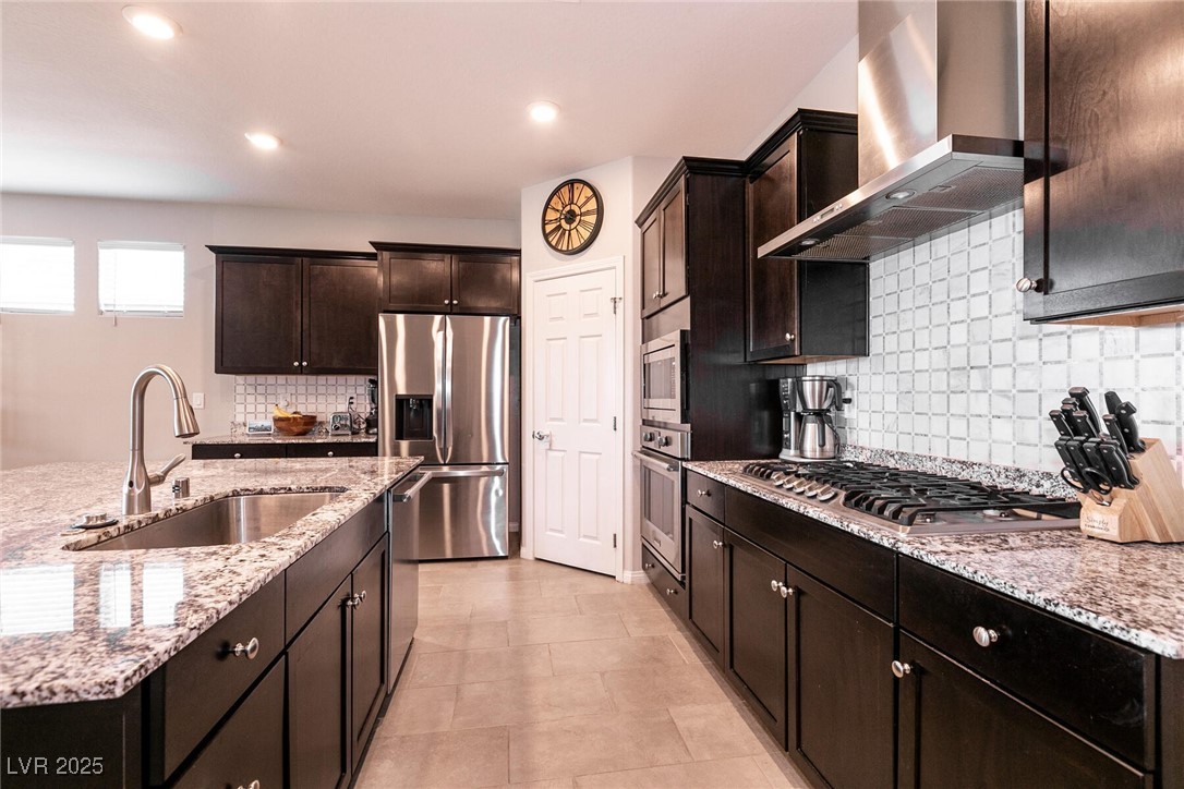 Kitchen with dark wood cabinets, granite counters, stainless appliances, and a large sink island.