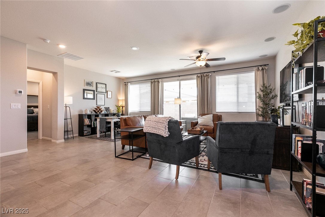 Living room with dark armchairs, leather seating, and large windows with blinds.