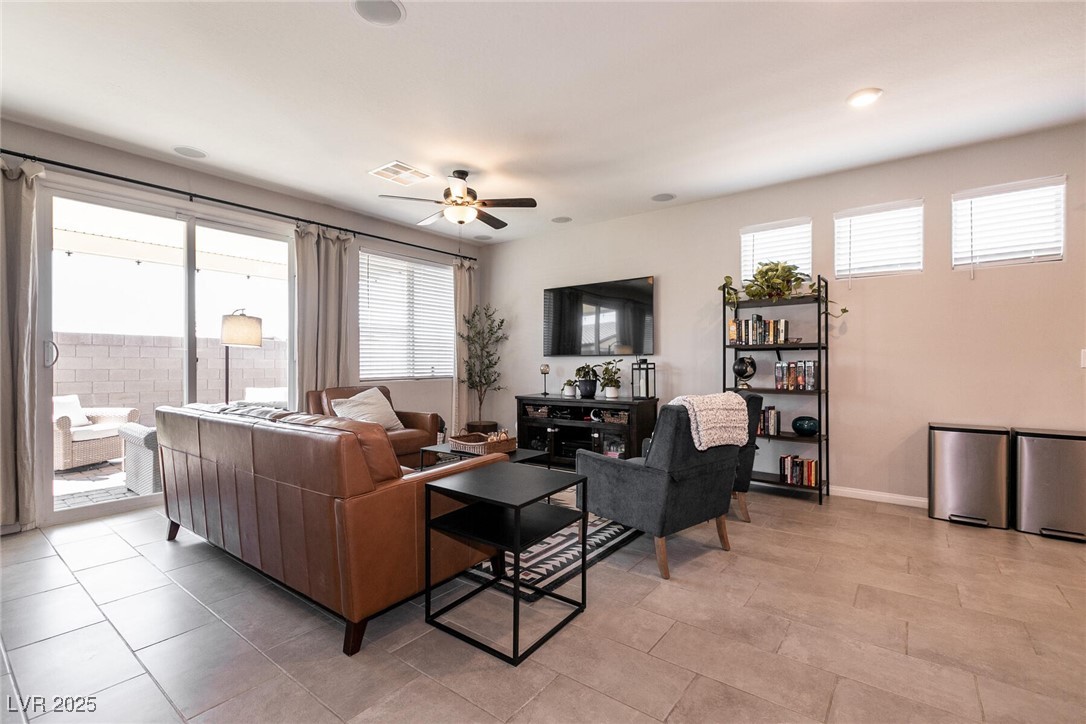 Living room with leather sofas, a gray armchair, tiled floors and sliding doors to a patio.