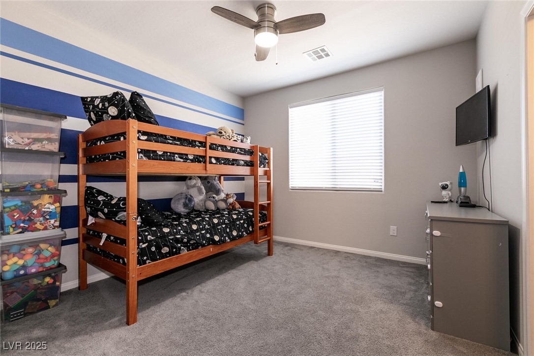 Bedroom with a wooden bunk bed, space-themed bedding, and blue-and-white striped accent wall.