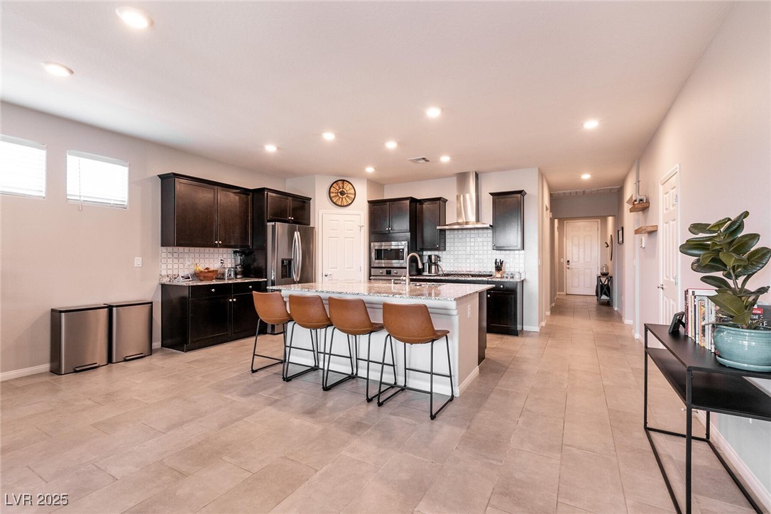 Kitchen with dark cabinets, stainless steel appliances, and a white island with four bar stools.