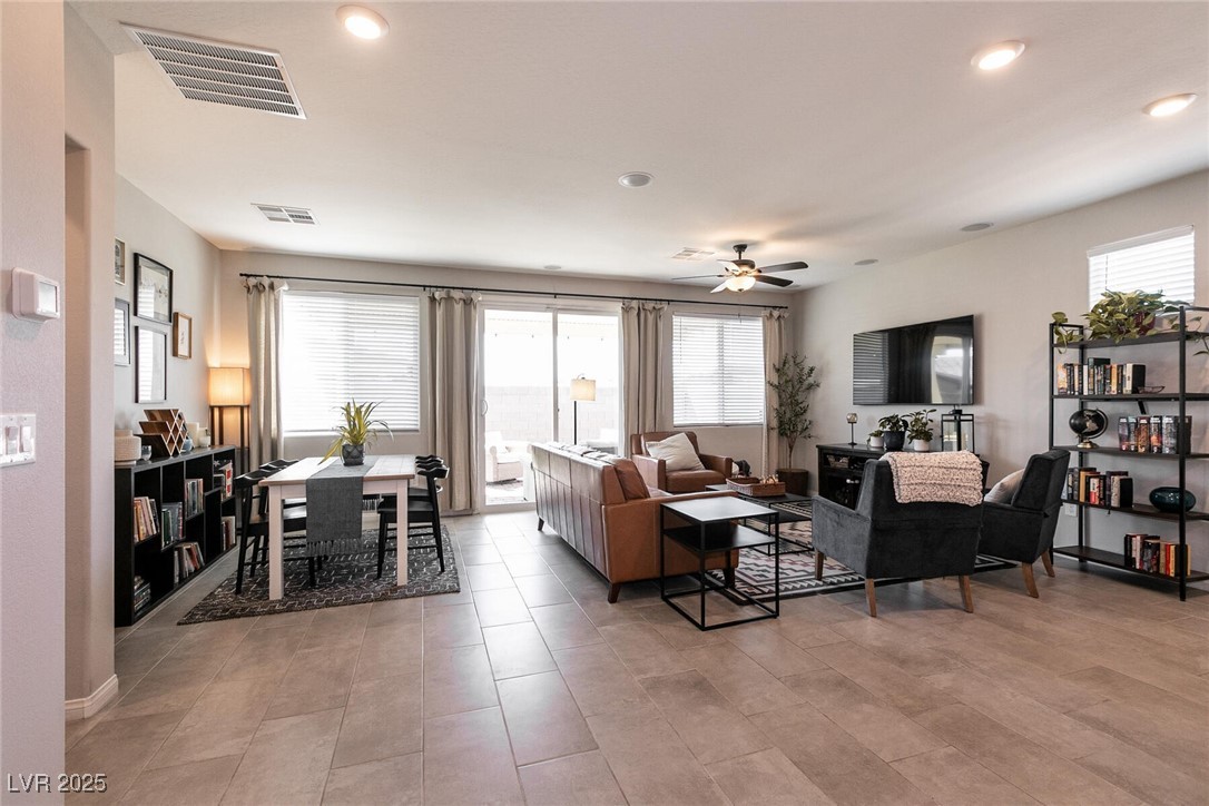 Open-plan living and dining room with tiled floors, sliding glass doors, and staged seating.