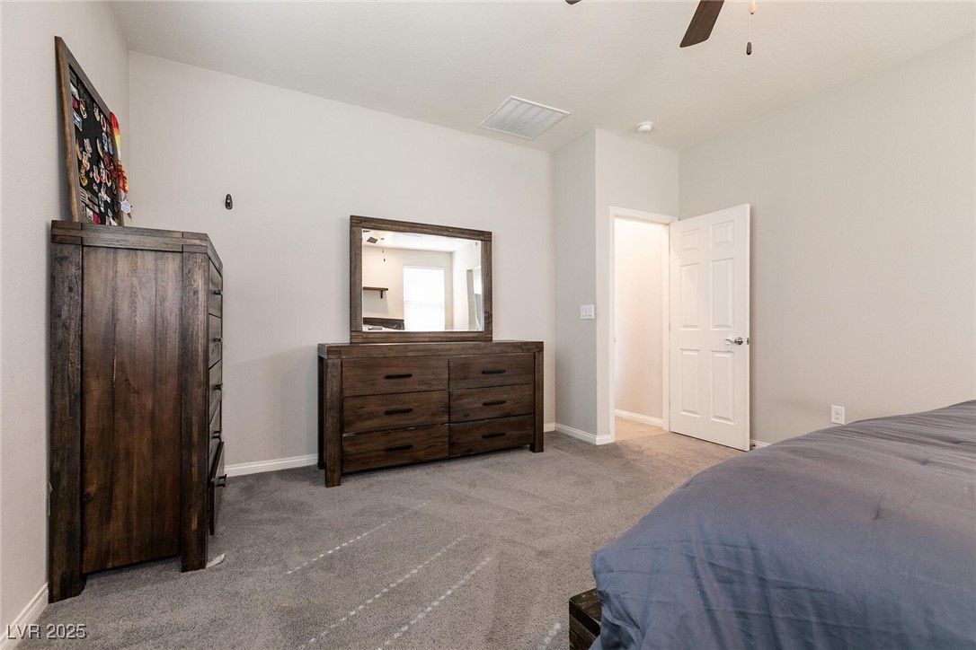 Bedroom with a blue-covered bed, dark wood furniture, gray carpet, and an open door.