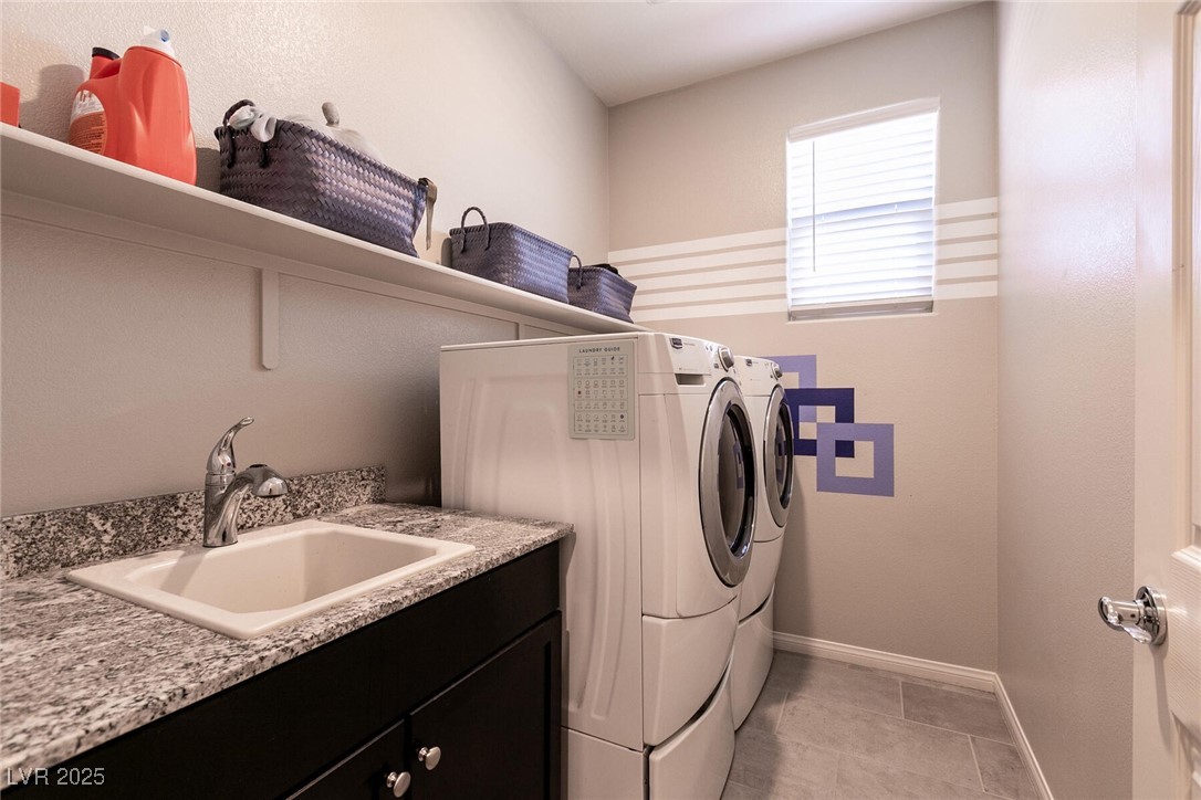 Laundry room with a granite-topped utility sink, front-loading washer and dryer, and storage shelf.