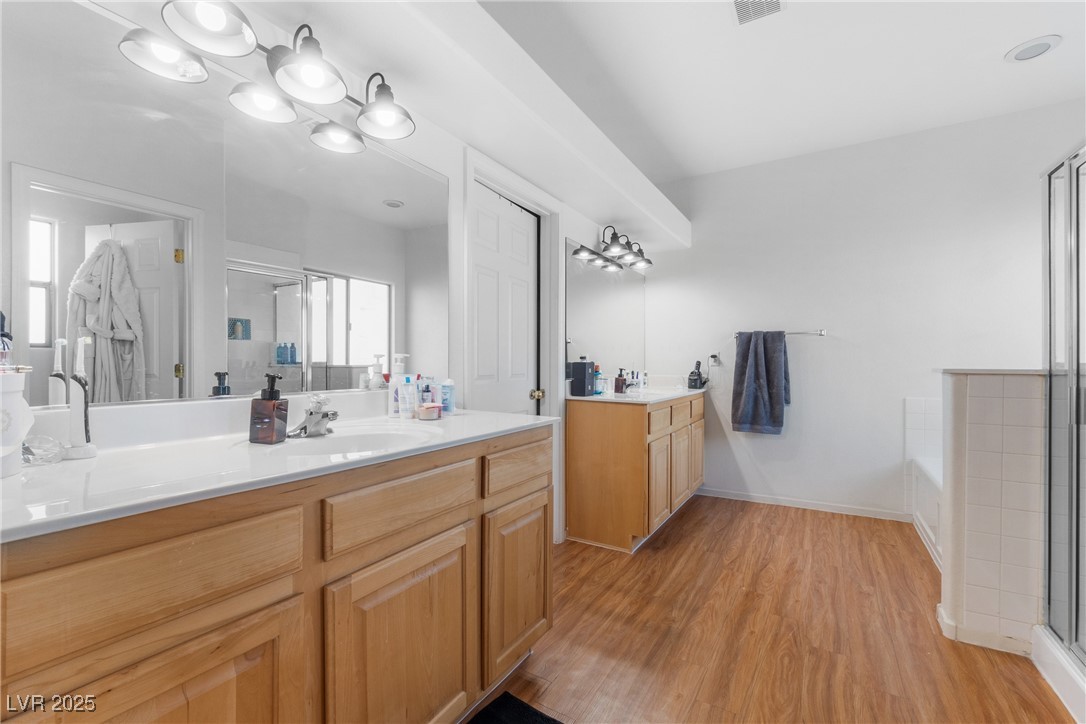 Spacious bathroom with a long double-sink wood vanity, large mirrors, and wood-look flooring.