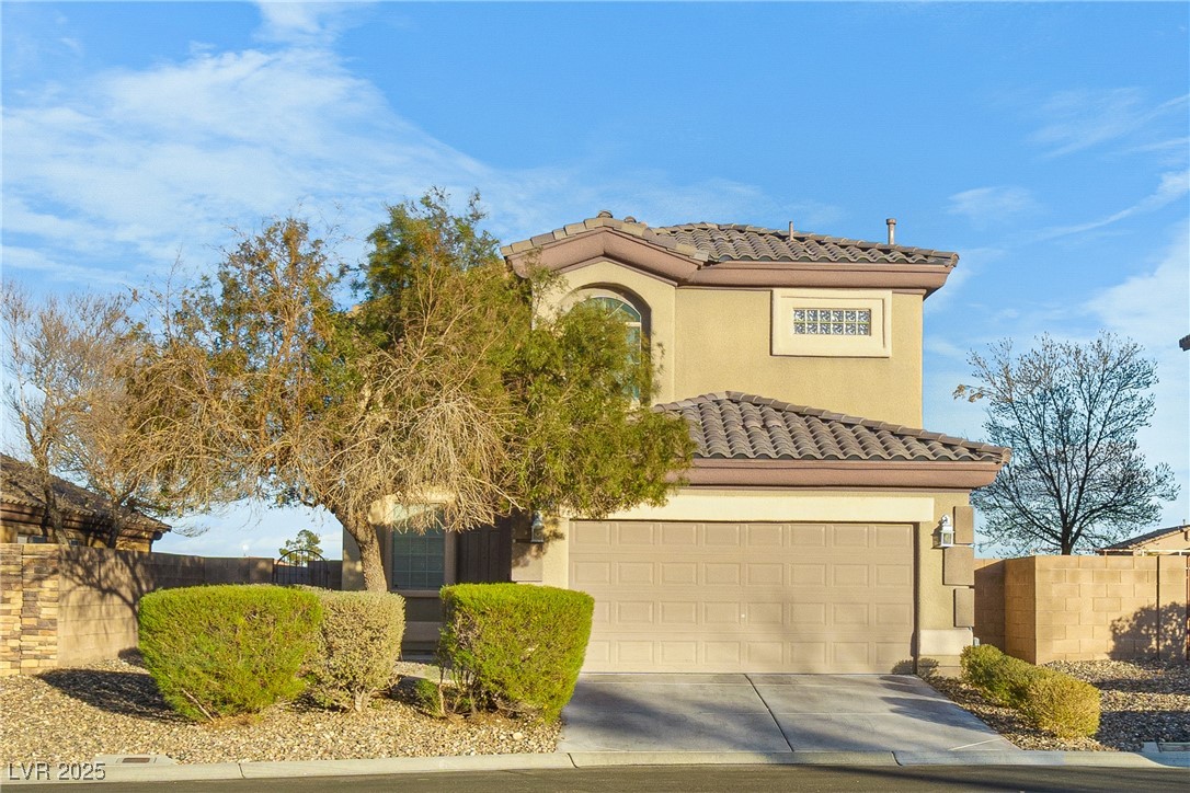Two-story beige home with a tile roof, two-car garage, and desert landscaping.