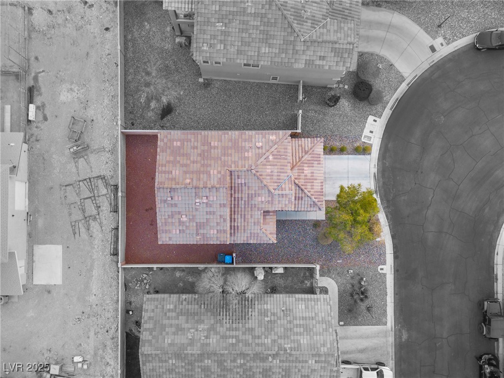 Aerial view of a tile-roofed home with gravel landscaping beside a curved street.