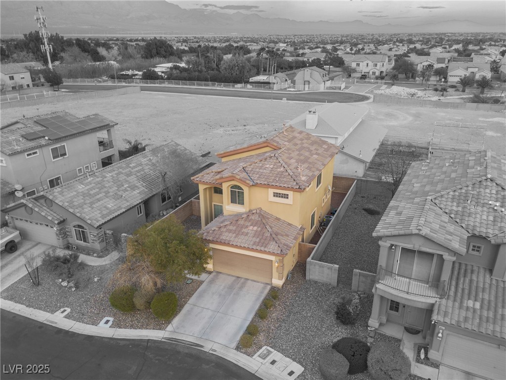 Yellow two-story house with a tile roof and attached garage, viewed from above with mountains in the distance.