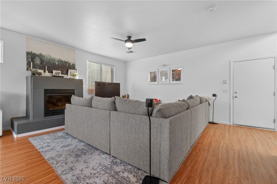 Living room with a gray sectional, dark fireplace, wood floors, and patterned rug.