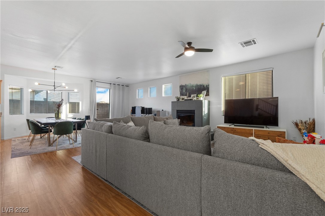 Open-plan living and dining room with a gray sectional, fireplace, and wood-look flooring.
