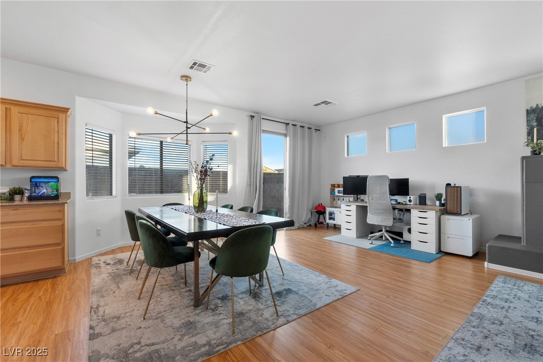 Open dining and work area with green chairs, a computer desk, and warm wood flooring.