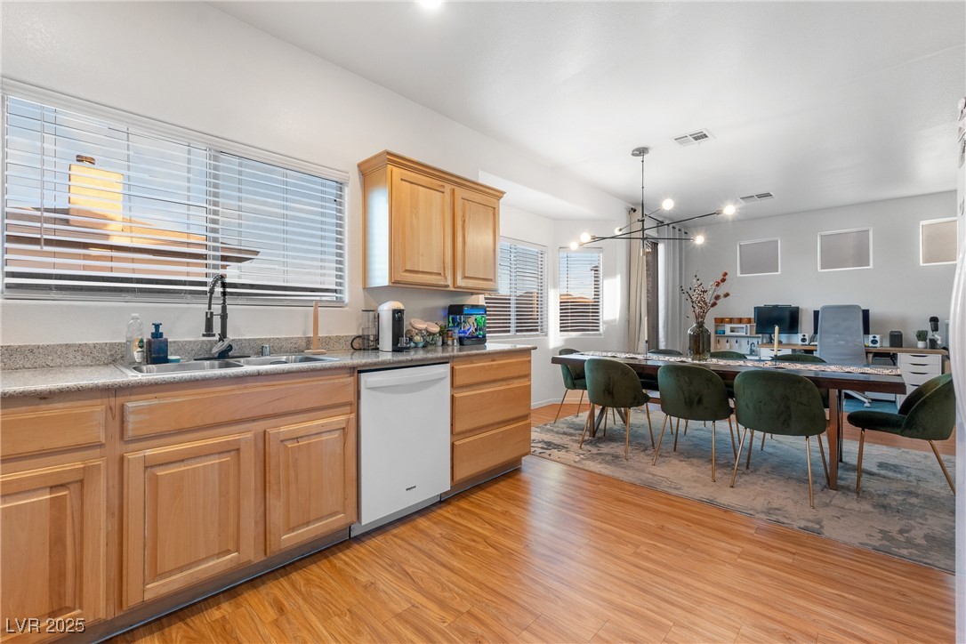 Kitchen and dining area with wood cabinets, granite counters, and green dining chairs.
