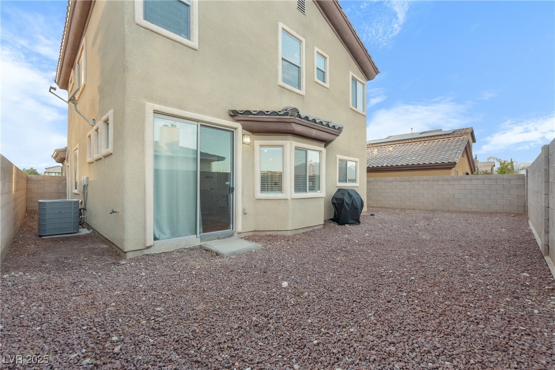 Two-story stucco house with a gravel backyard, sliding glass door, and block walls.