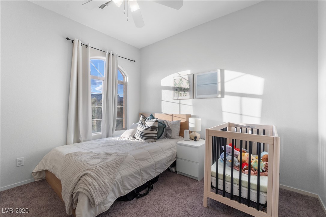Bright bedroom with a wooden crib beside a bed and tall arched windows.