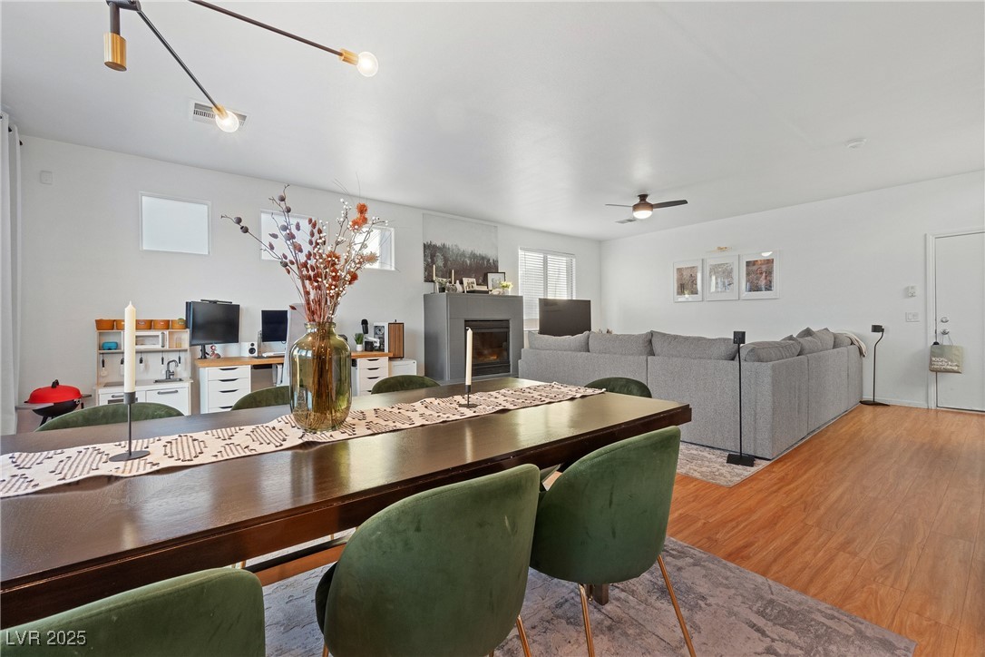 Open-plan dining and living room with green chairs, a gray sectional, and a fireplace.