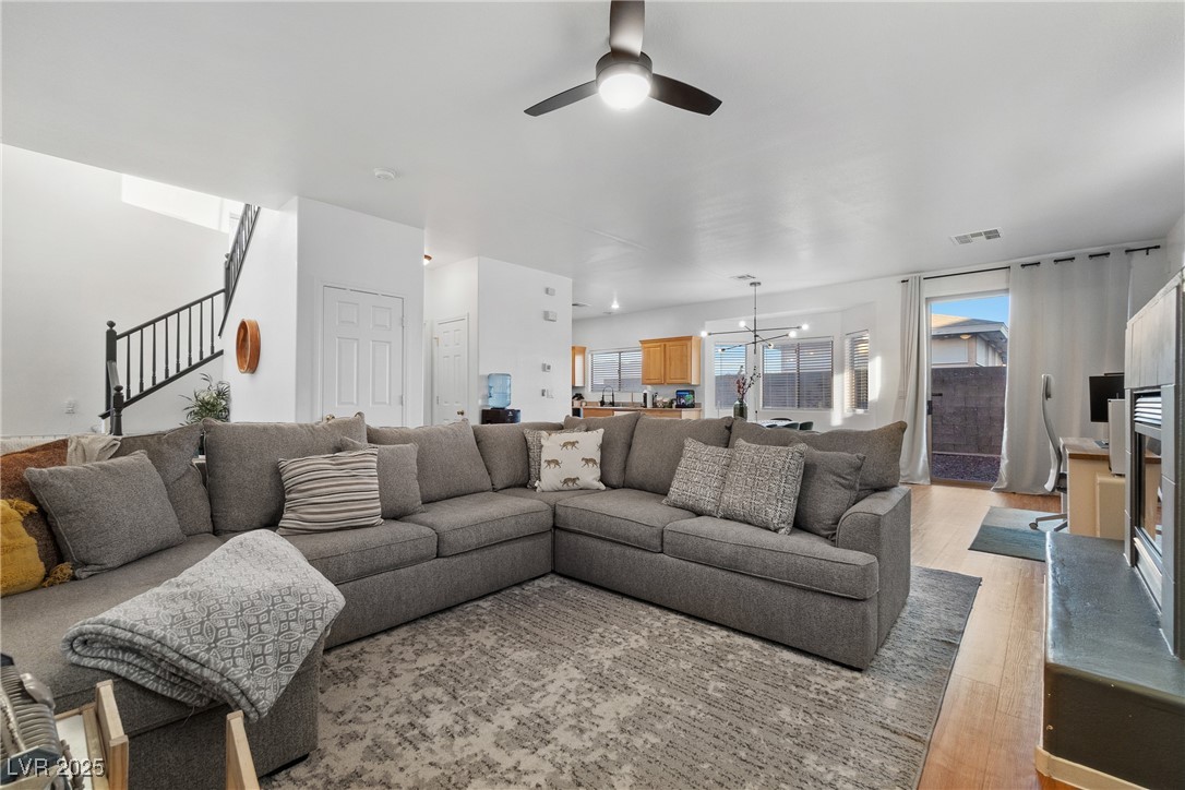 Living room with a large gray sectional, patterned rug, staircase, and open kitchen beyond.