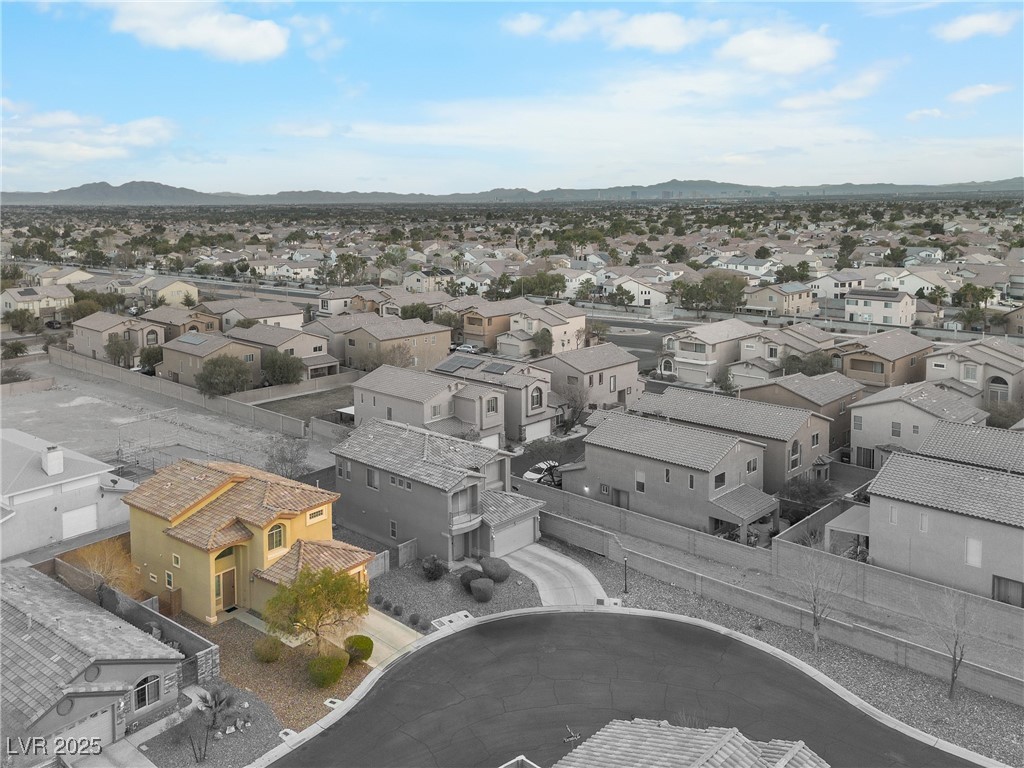 Yellow two-story home on a Las Vegas cul-de-sac, with surrounding neighborhood and distant mountains.