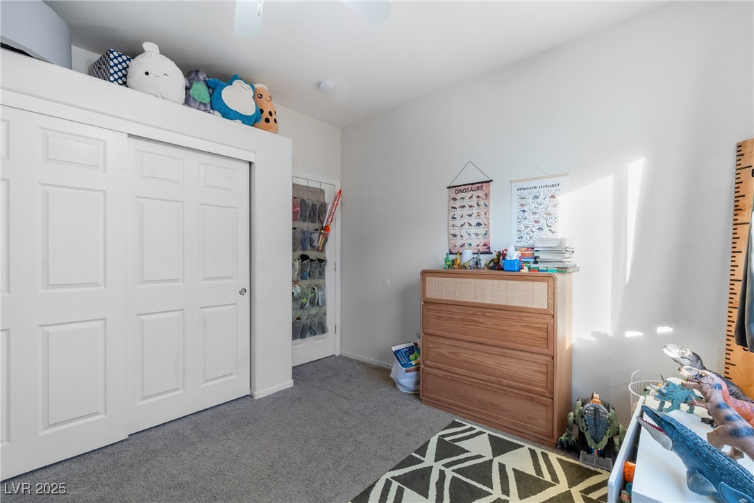 Child’s bedroom with white closet doors, a wooden dresser, dinosaur decorations, and a geometric rug.