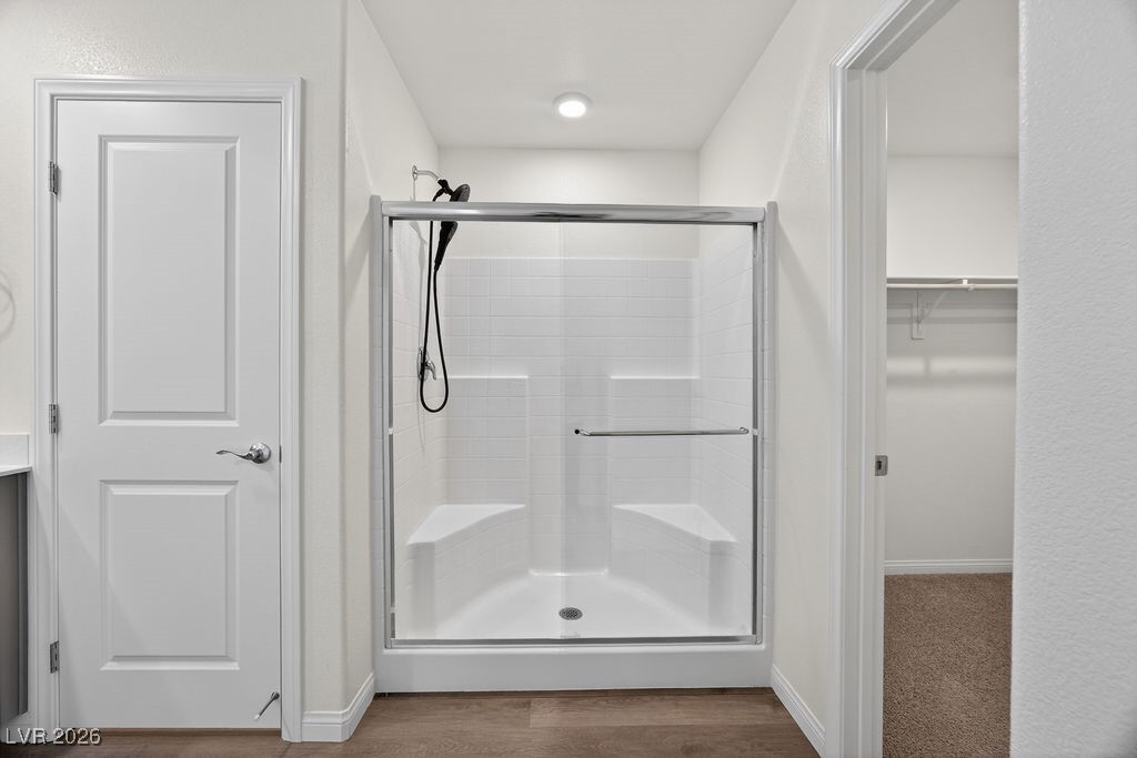 Bathroom with a glass-enclosed shower, built-in seats, and a black showerhead.