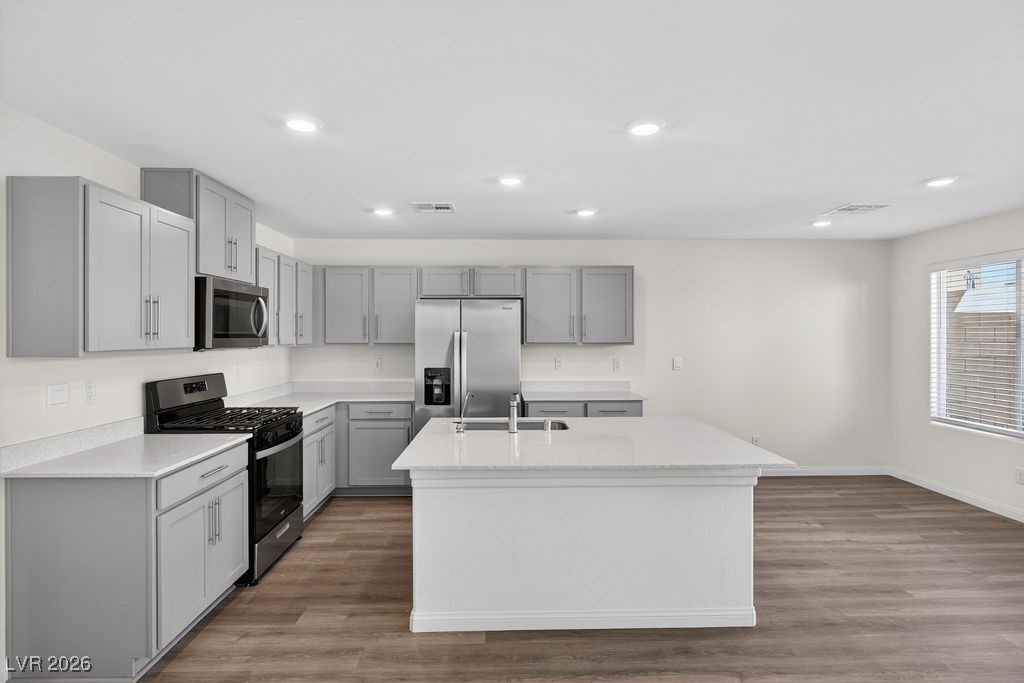 Vacant kitchen with gray cabinets, stainless steel appliances, and a large white island.