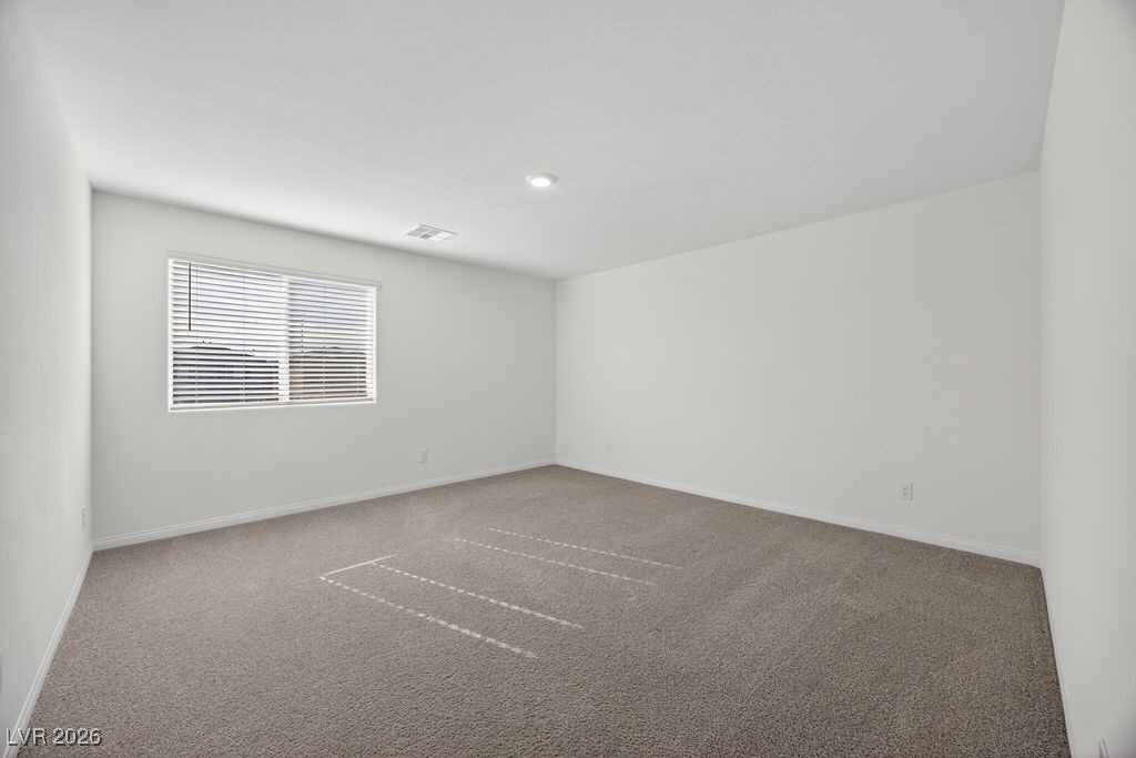 Empty carpeted room with a window fitted with horizontal blinds.