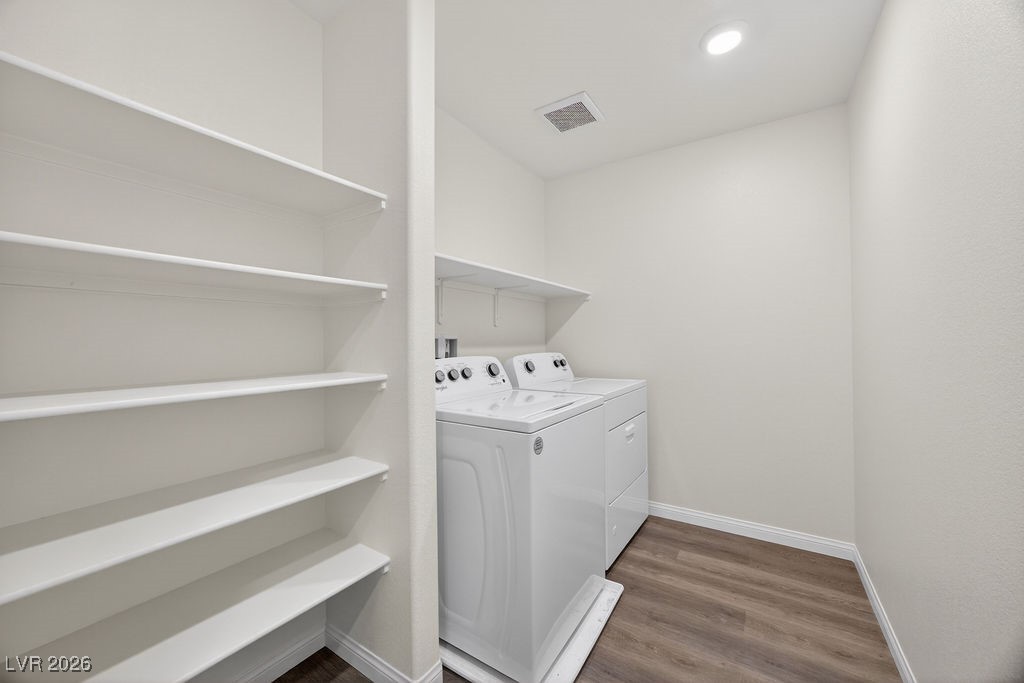 Laundry room with a white washer and dryer beside multiple built-in storage shelves.