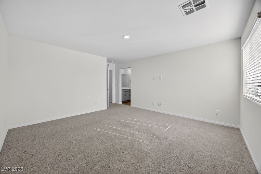 Empty carpeted room with a wide window and a doorway to the kitchen.