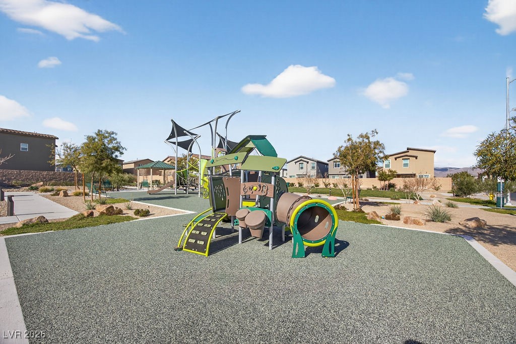 Neighborhood playground with colorful climbing structures and a tunnel slide on a rubberized surface.