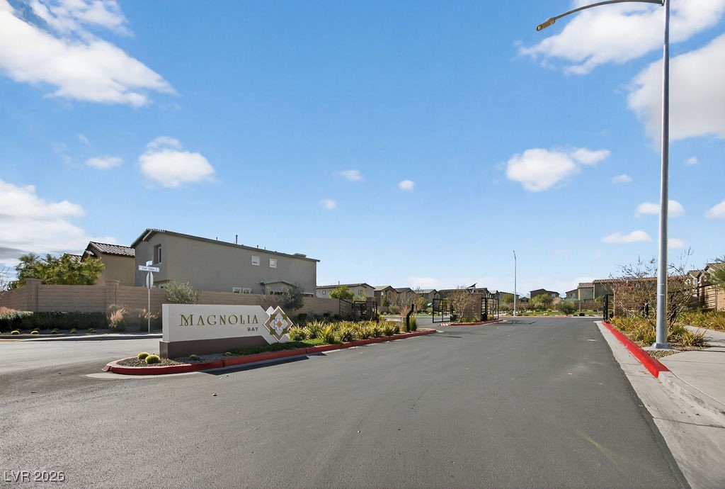 Magnolia Bay community entrance sign beside a landscaped street lined with homes.